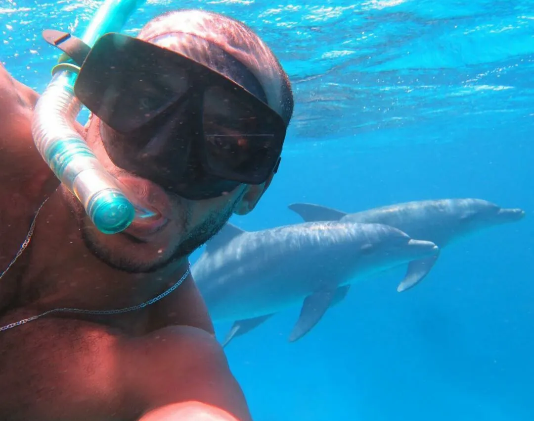 Snorkelaar zwemt op respectvolle afstand naast een wilde dolfijn in de Rode Zee bij Hurghada