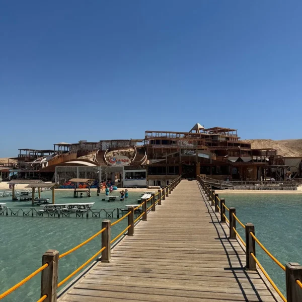 Lange houten pier met gele relingen richting de strandlocatie Orange Bay