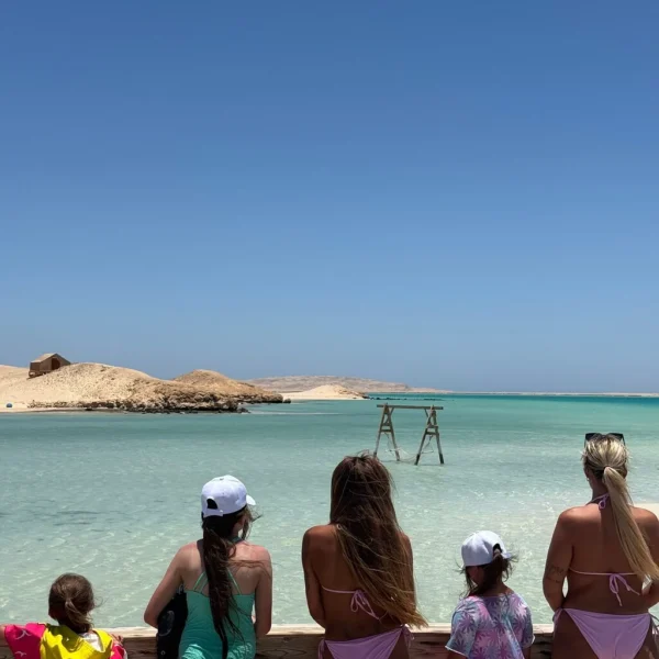 Reizigers met kinderen kijken vanaf een houten platform uit over het water bij Orange Bay
