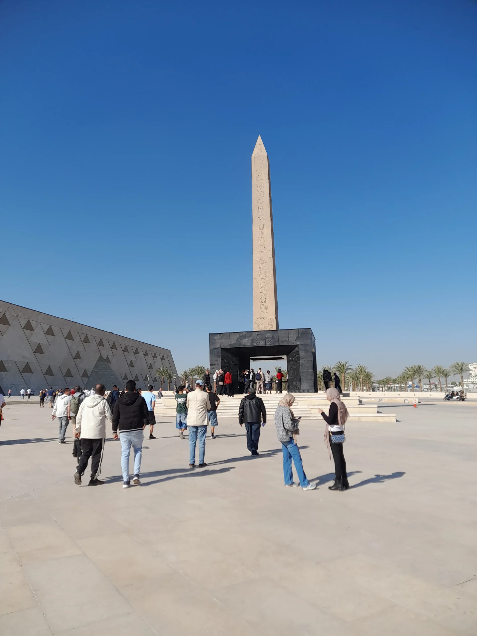 Entree van het Grand Egyptian Museum bij Caïro met obelisk en bezoekers