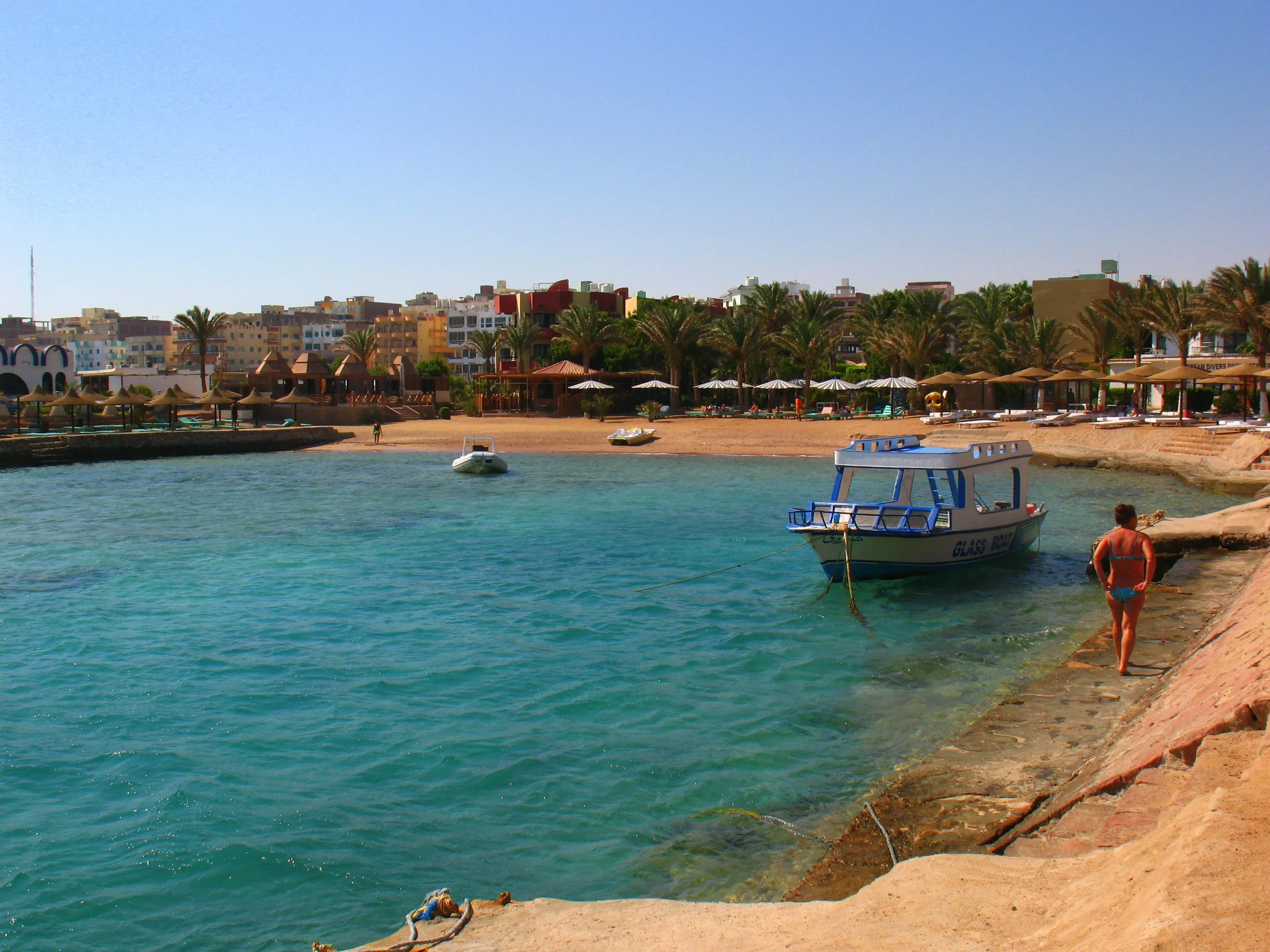 Rustig strand met turquoise water en een boot aan de Rode Zee in Hurghada, Egypte