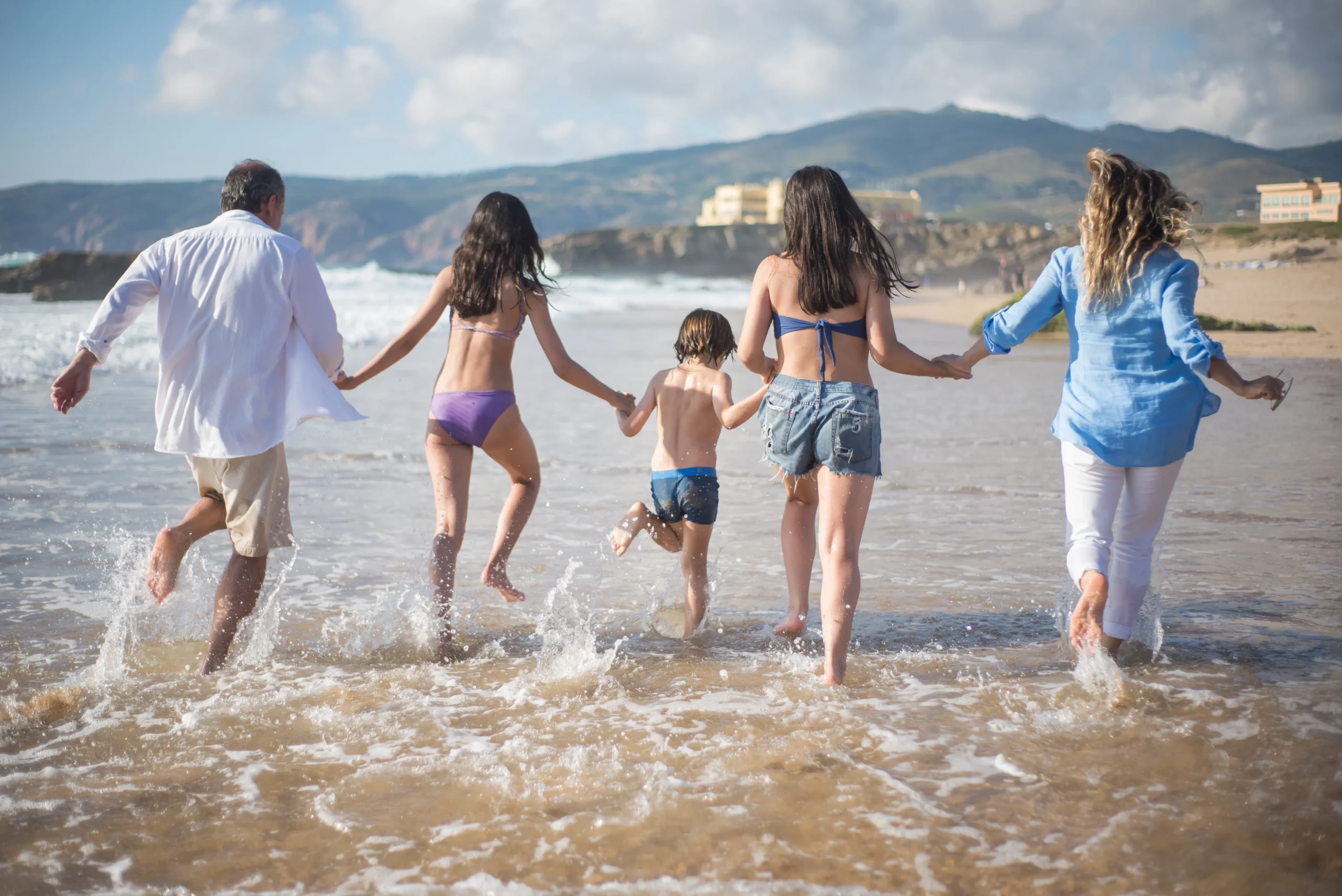 Gezin met kinderen rent samen lachend het zeewater in op een zonnig strand in Hurghada